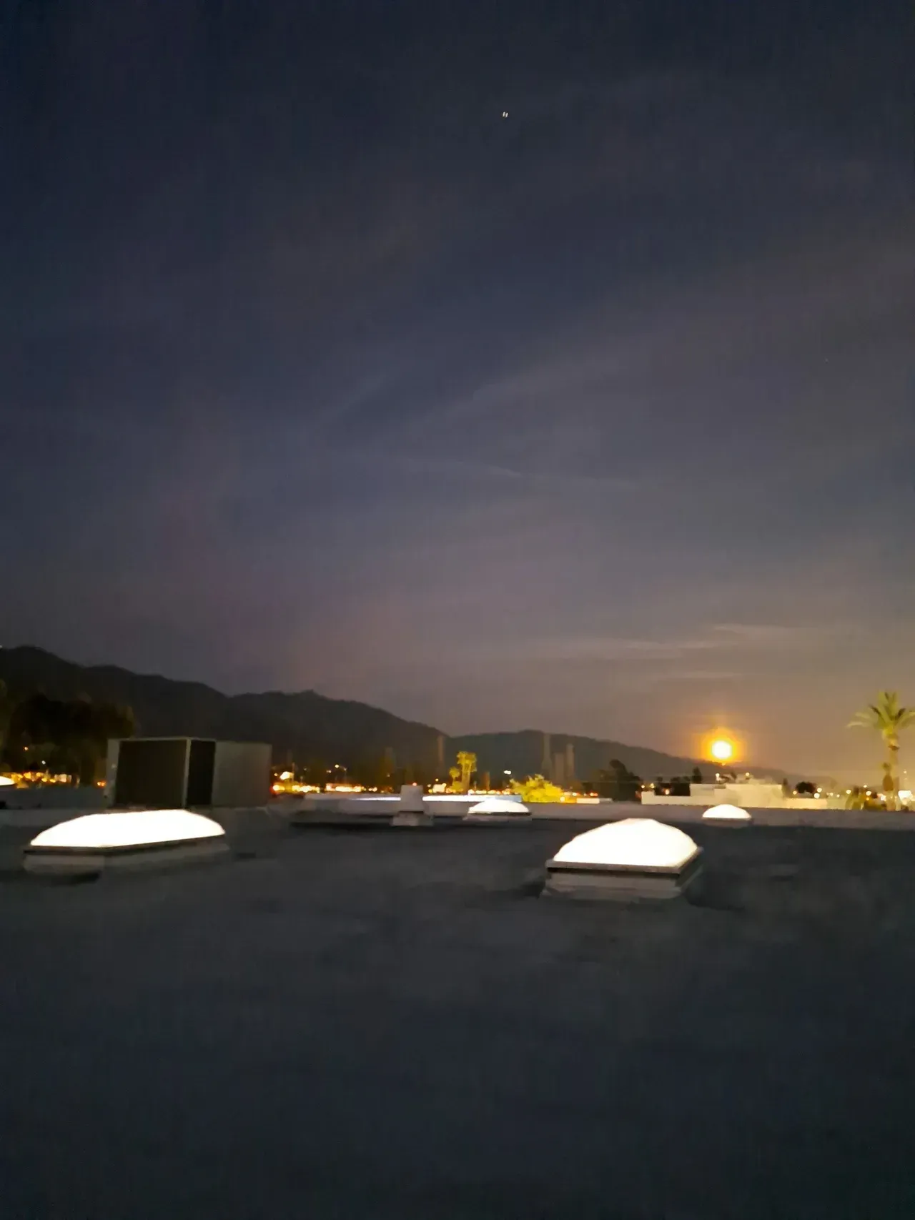 A rooftop at night with a full moon in the sky