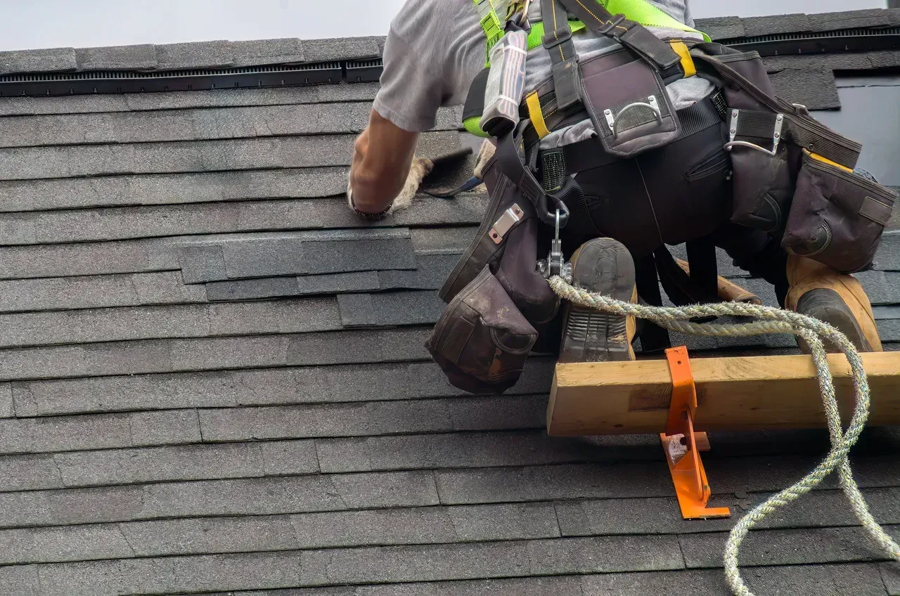 A man is working on a roof with a rope attached to him