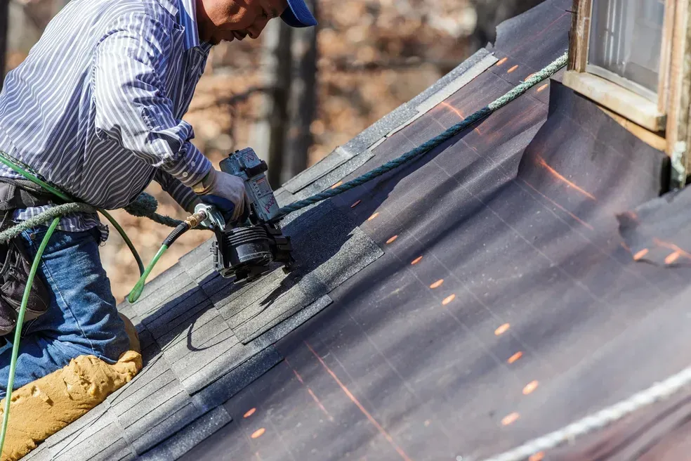 A man is working on a roof with a tool.