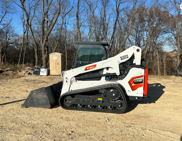 White and orange Bobcat compact track loader on a construction site.