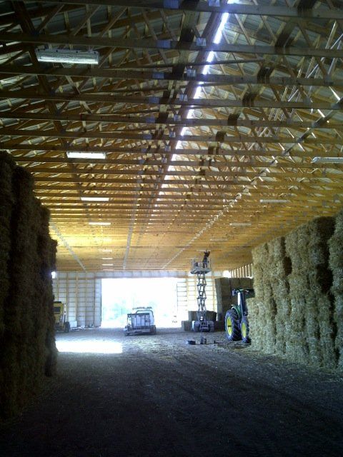 A warehouse filled with hay bales under a wooden roof