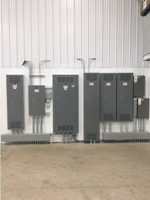 A row of electrical boxes are lined up against a white wall.