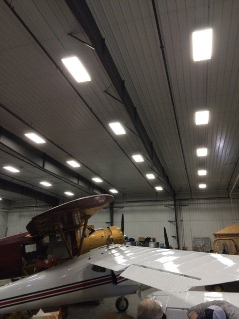 A plane in a hangar with a few lights on the ceiling