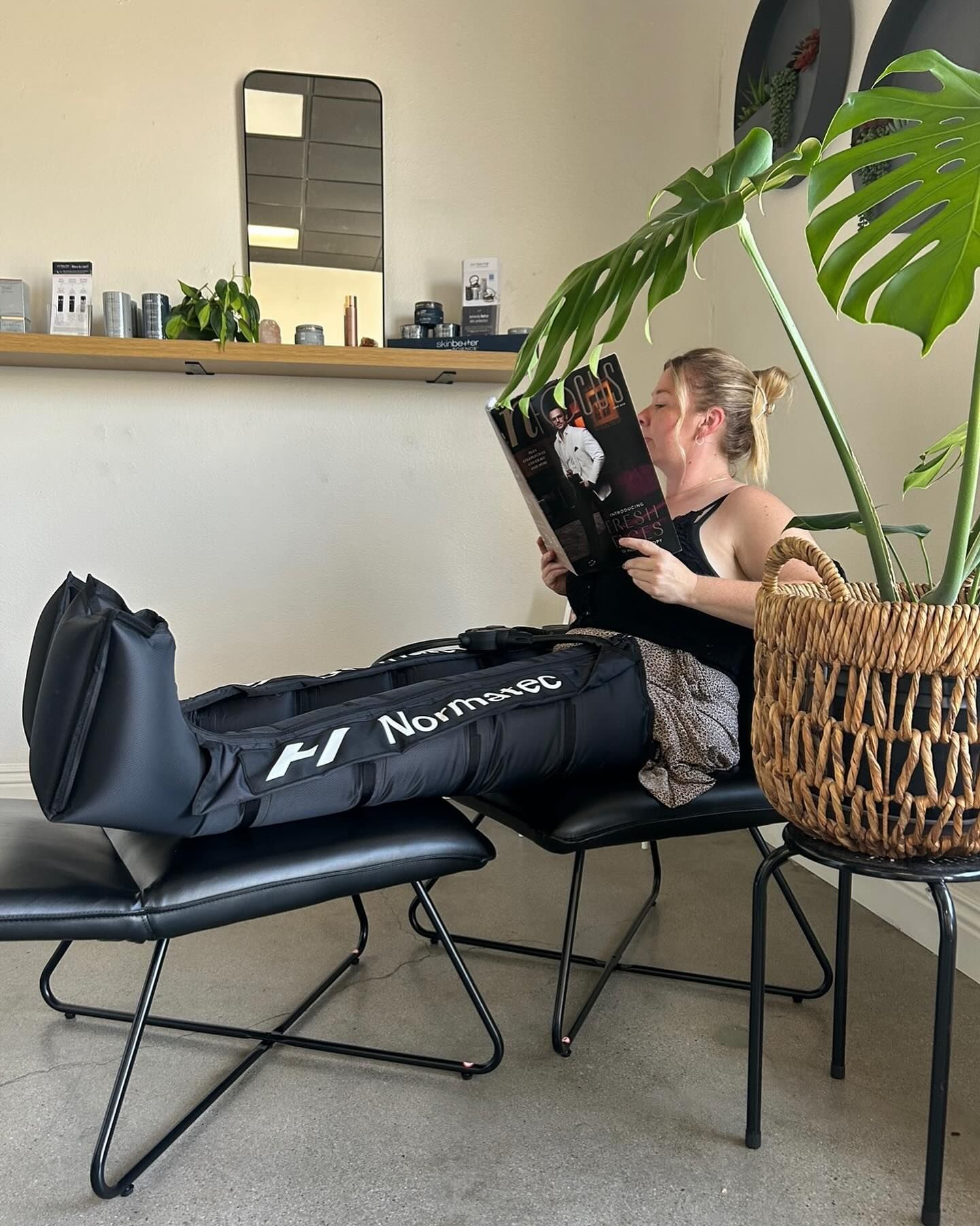 A woman is sitting on a chair reading a book.