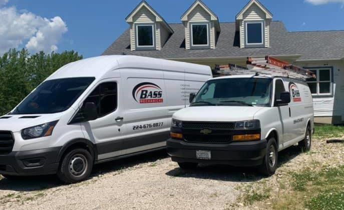 Two white vans are parked in front of a house.