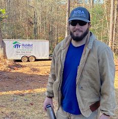 A man is standing in front of a truck in the woods.