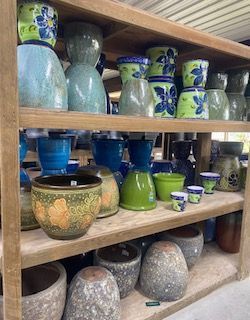 Shelves filled with assorted blue, green, and patterned ceramic pots and planters