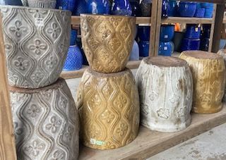 Decorative carved wooden stools in gray, gold, and white on a shop shelf