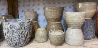 Assorted ceramic flower pots and planters in beige, gray, and speckled patterns on a shelf