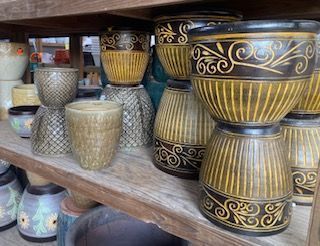 Shelves filled with assorted ceramic flower pots and planters in gold, black, and pastel patterns