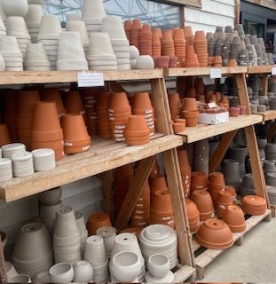 Shelves of terracotta and white plant pots stacked outdoors at a garden center