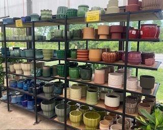 Shelves of colorful ceramic plant pots on display in a garden store