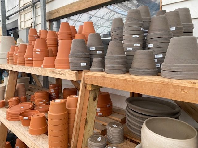 Clay flower pots stacked on wooden shelves in a shop.