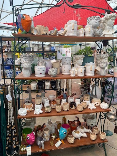 Shelves filled with various decorative pots, including animal and face designs, in a shop setting.