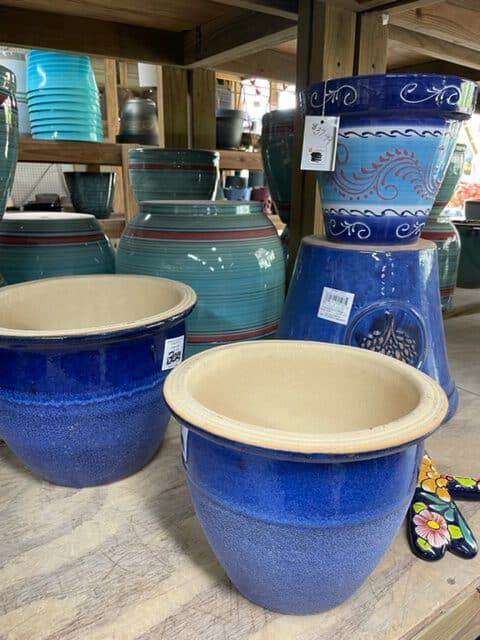 Blue and teal glazed ceramic planters on display at a garden shop.