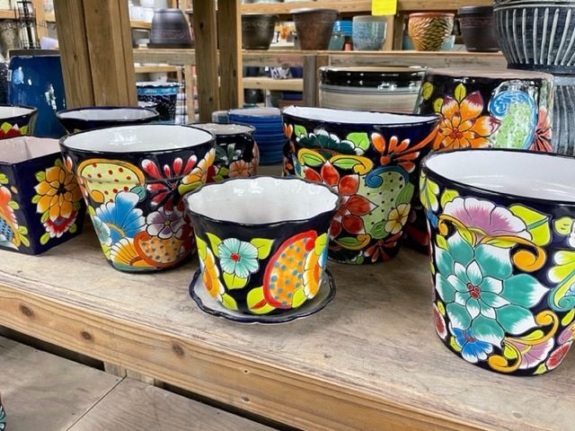 Colorful floral-patterned ceramic pots on a wooden shelf in a store.