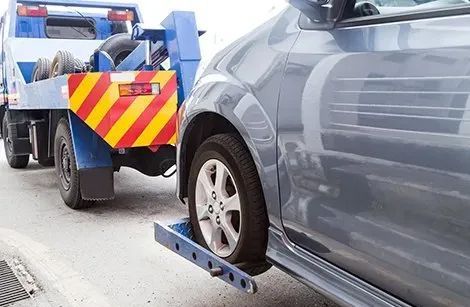 A tow truck is towing a car on the side of the road.