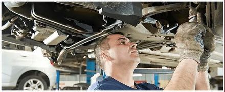 A man is working under a car in a garage.