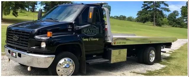 A black tow truck is parked on the side of the road.