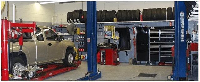 A truck is sitting on a lift in a garage.