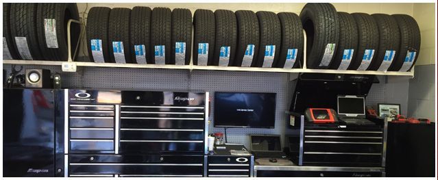 A row of tires are lined up on a shelf in a garage