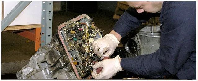 A man wearing gloves is working on a car engine