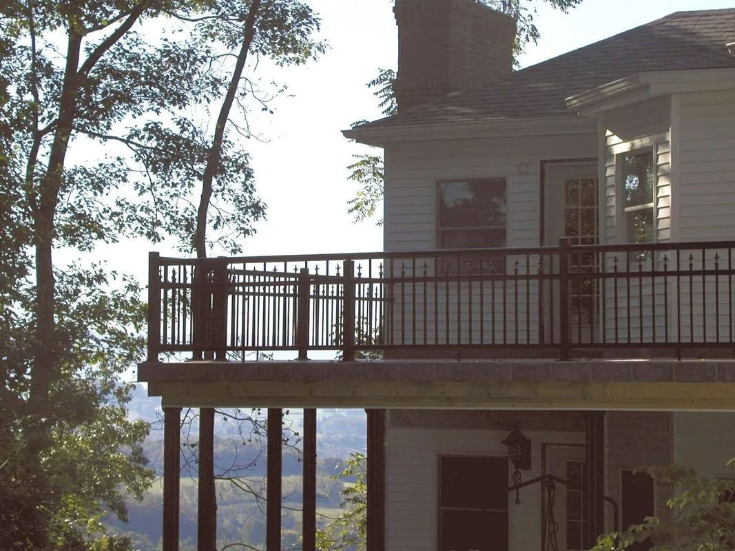 Wooden balcony on a white house overlooking trees and a hazy landscape