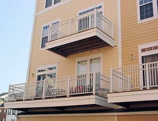 Apartment building with beige siding and stacked balconies with white railings