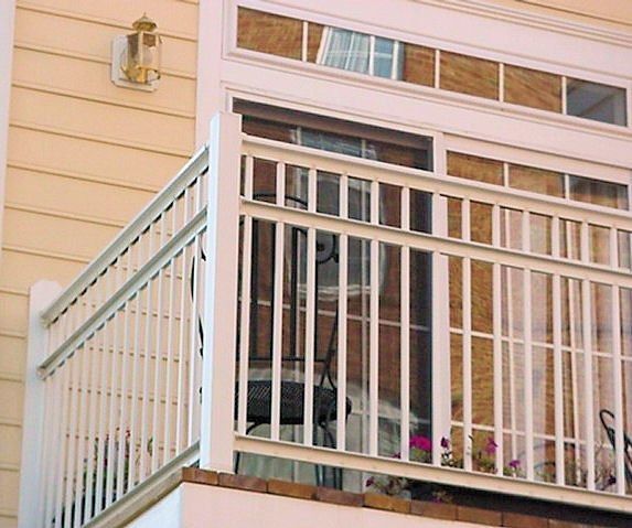 Porch with white railings on a beige house exterior and a wall-mounted light fixture