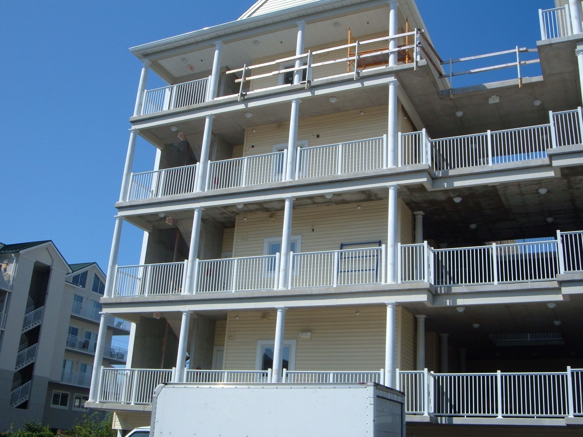 Multi-story apartment building with white balconies against a clear blue sky