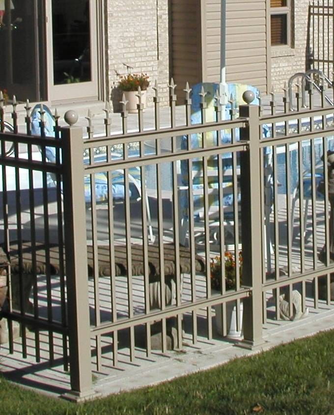 Metal fence around a backyard patio with a covered pool and house exterior