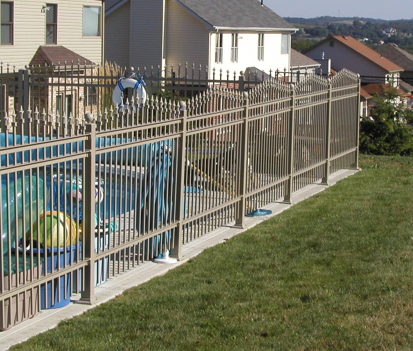 Blue fenced playground beside houses with a grassy yard and a person in the distance
