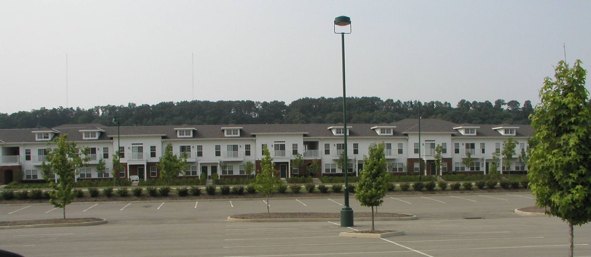 Empty parking lot with a row of townhouses and a lamppost in front