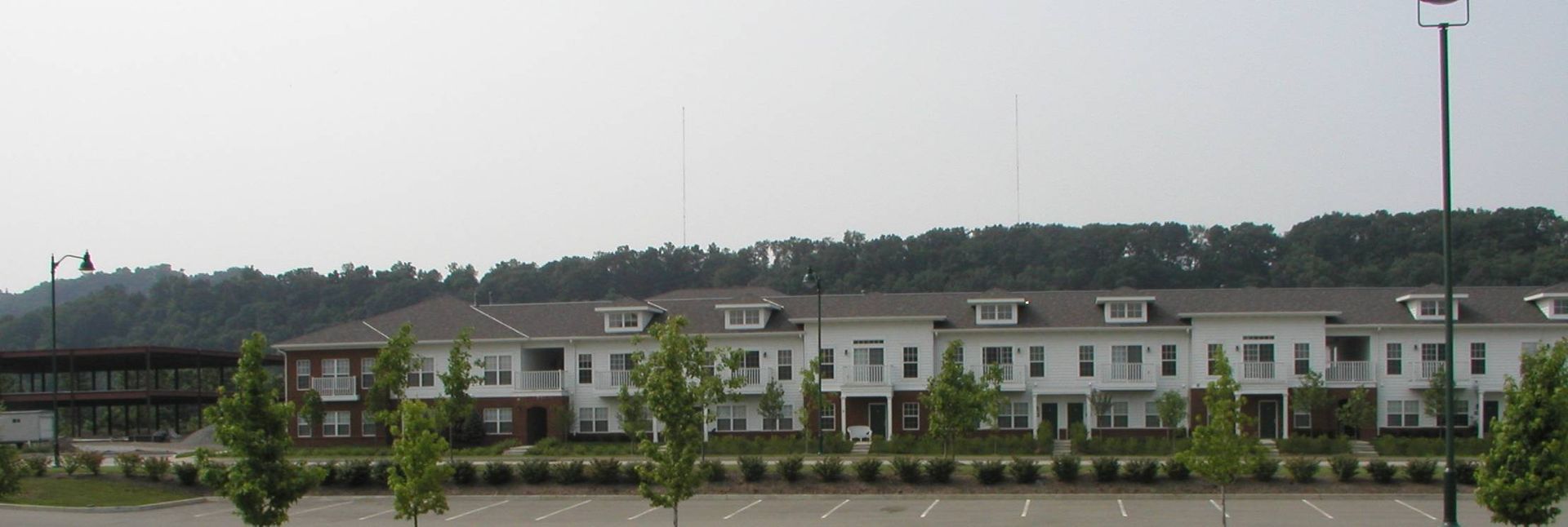 Row of white houses along a landscaped roadside with hills in the background