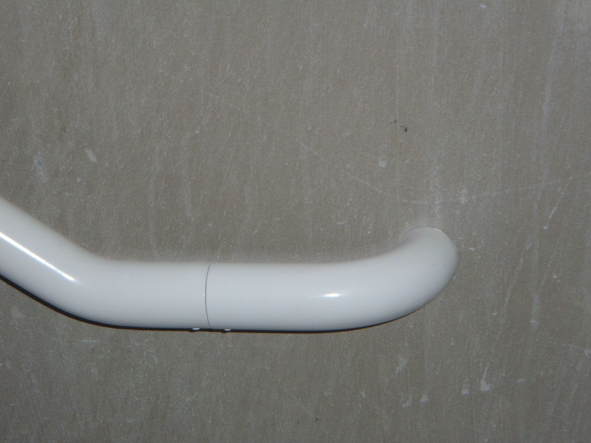 White curved grab bar mounted on a gray wall