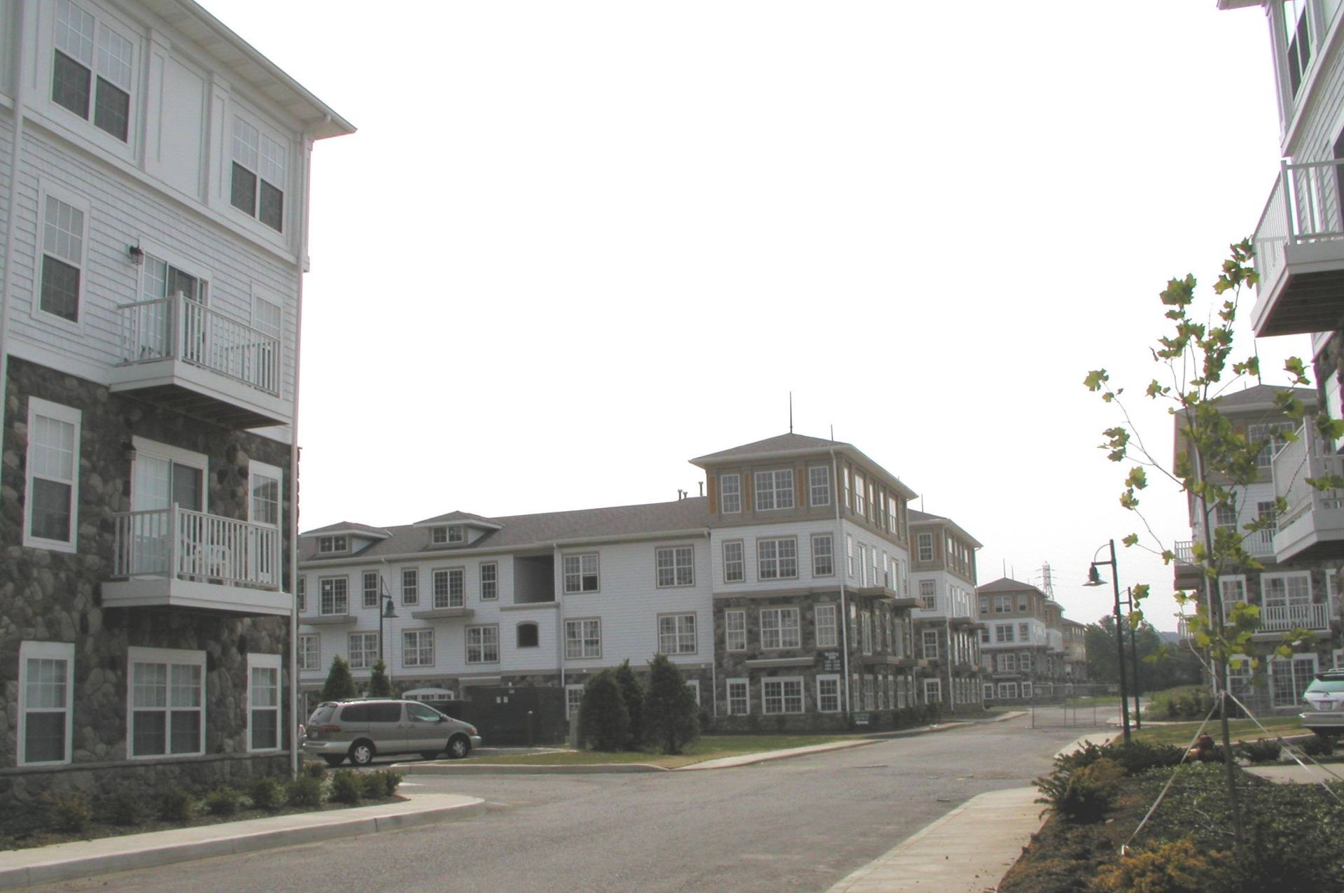 Modern apartment buildings lining a quiet residential street under a bright sky