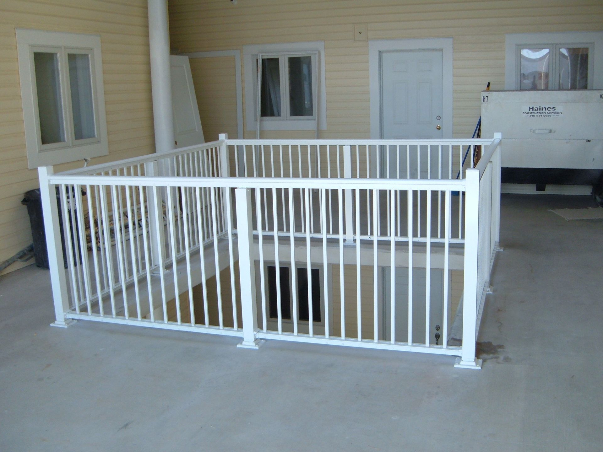 White metal railing enclosing a recessed doorway on a beige building exterior