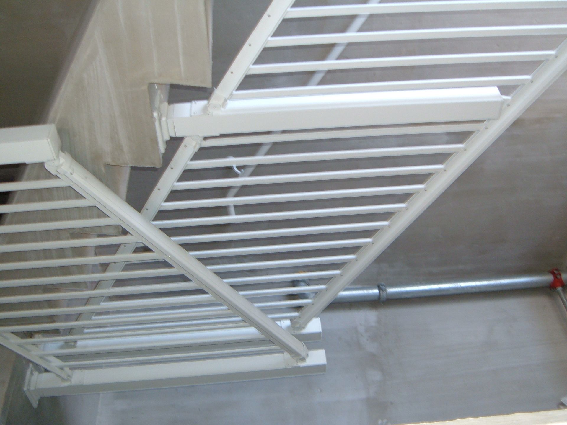 White metal railing or ladder structure mounted on a gray wall, viewed from below