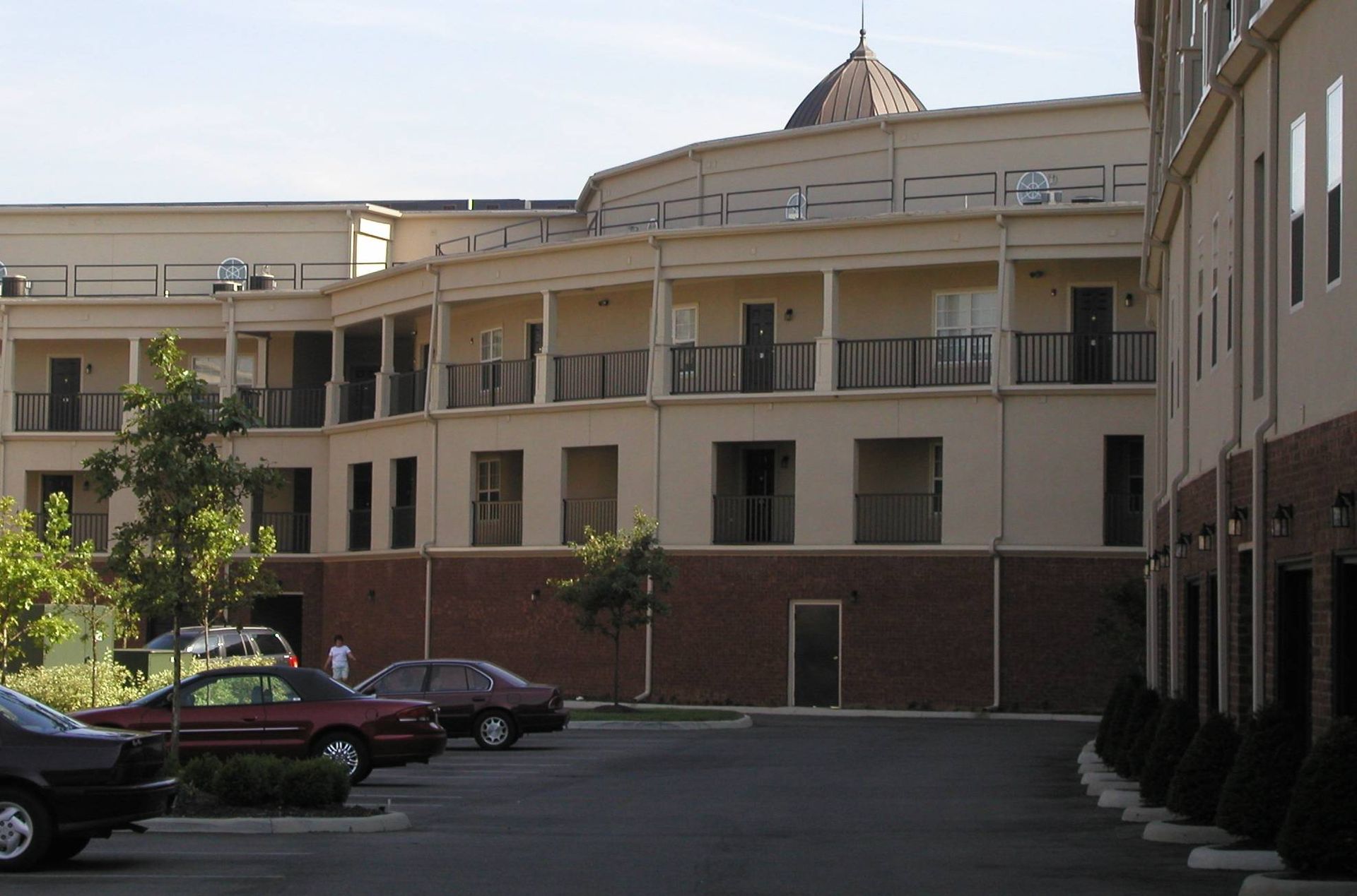 Apartment courtyard with parked cars and a beige building under a clear sky