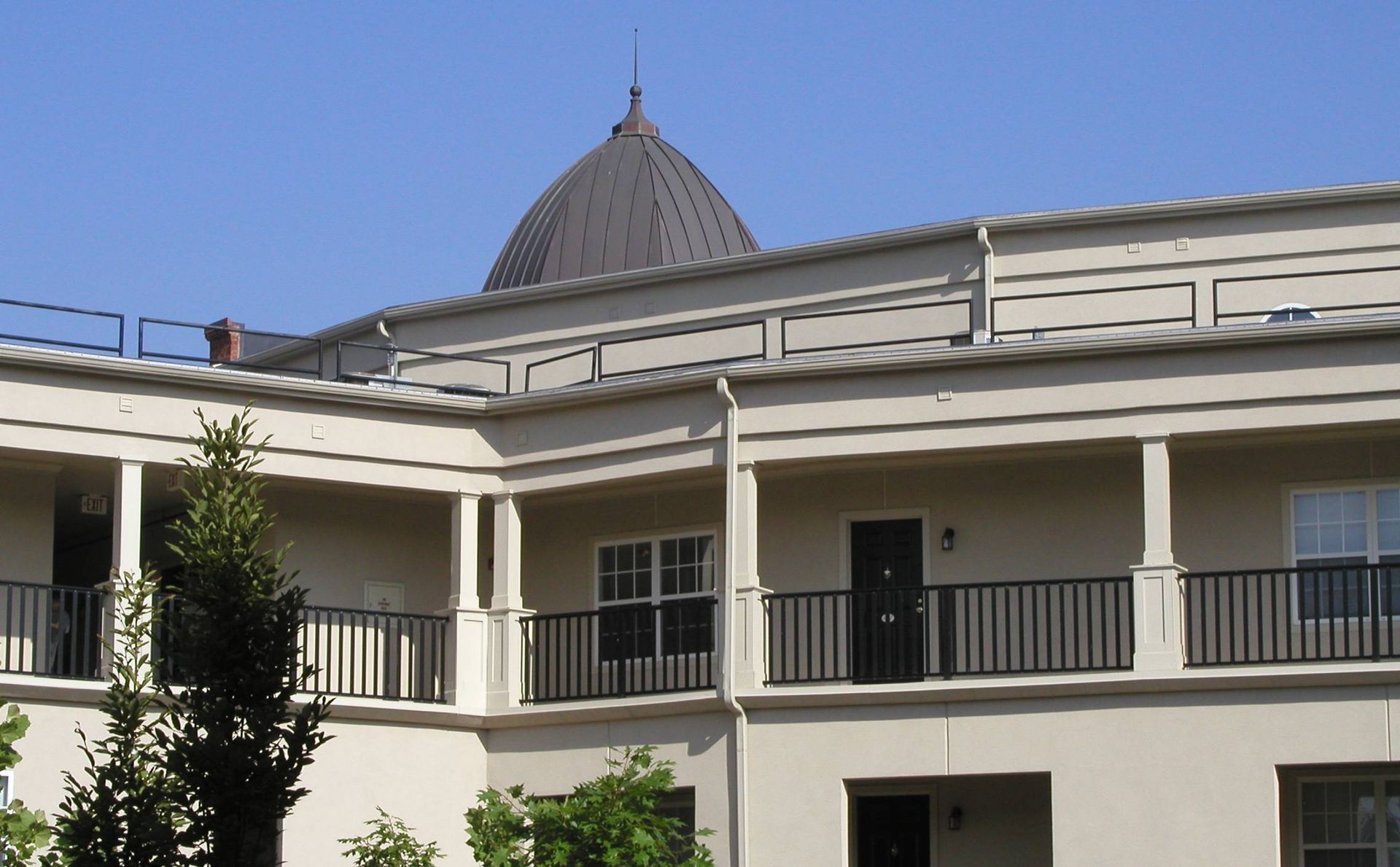 White building with balconies and a gray conical roof under a blue sky