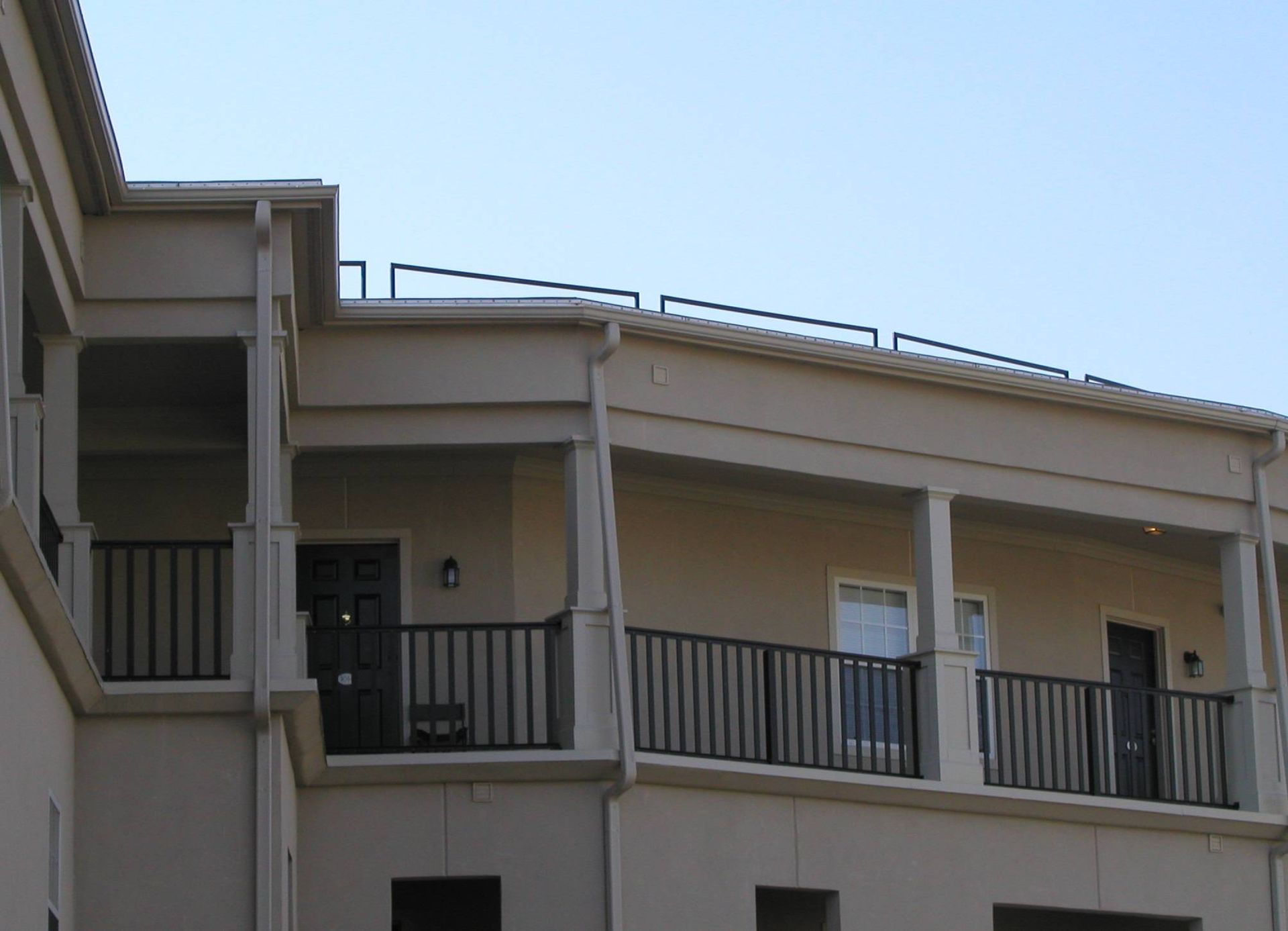 Balconies and railings on a beige apartment building under a clear blue sky
