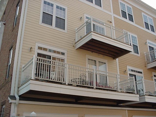Tan apartment building with balconies and white trim, viewed from below