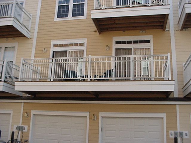 Apartment building facade with beige siding, white balconies, and two garage doors underneath
