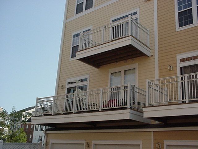Apartment building with beige siding and white balconies, viewed from below.