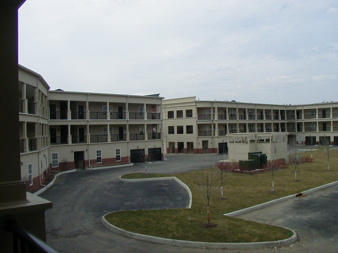 Curved driveway leading to a beige motel-style building with multiple balconies and a grassy courtyard