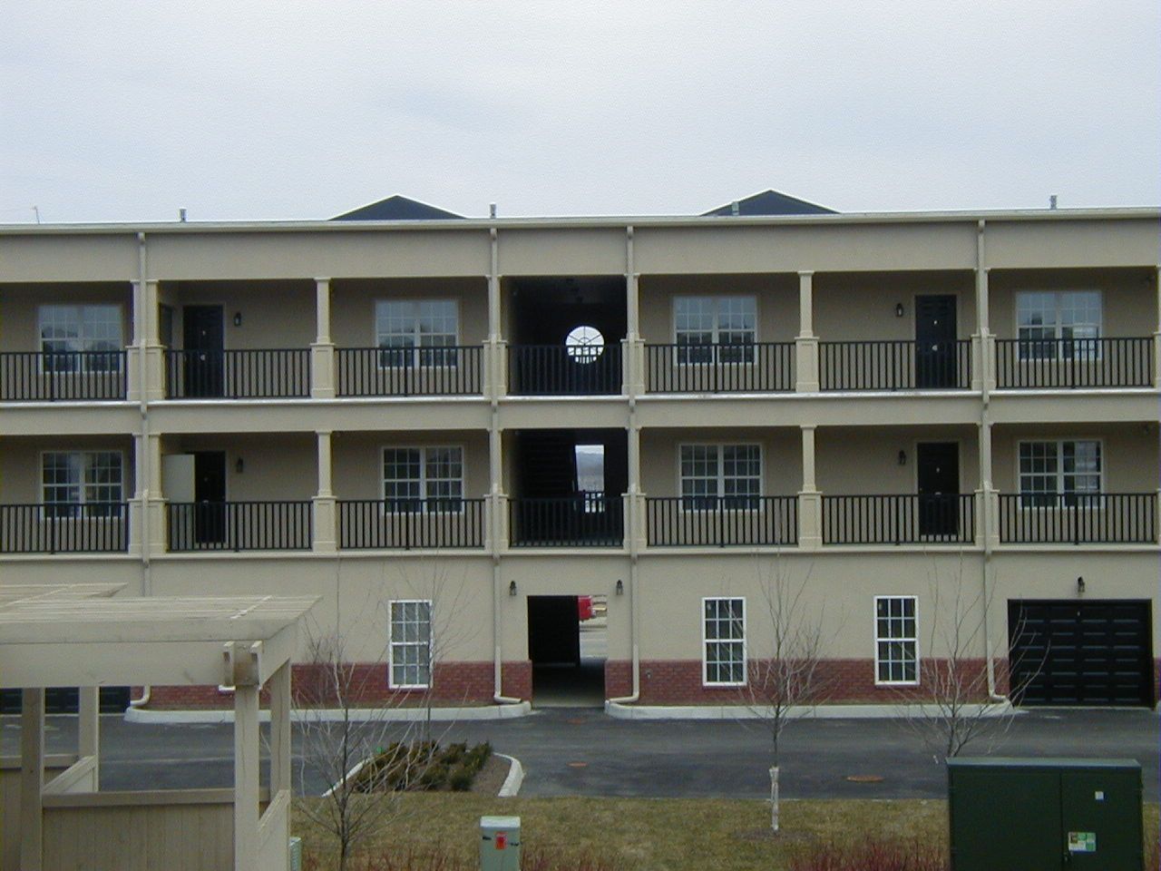 Three-story beige apartment building with balconies and a central stairwell entrance