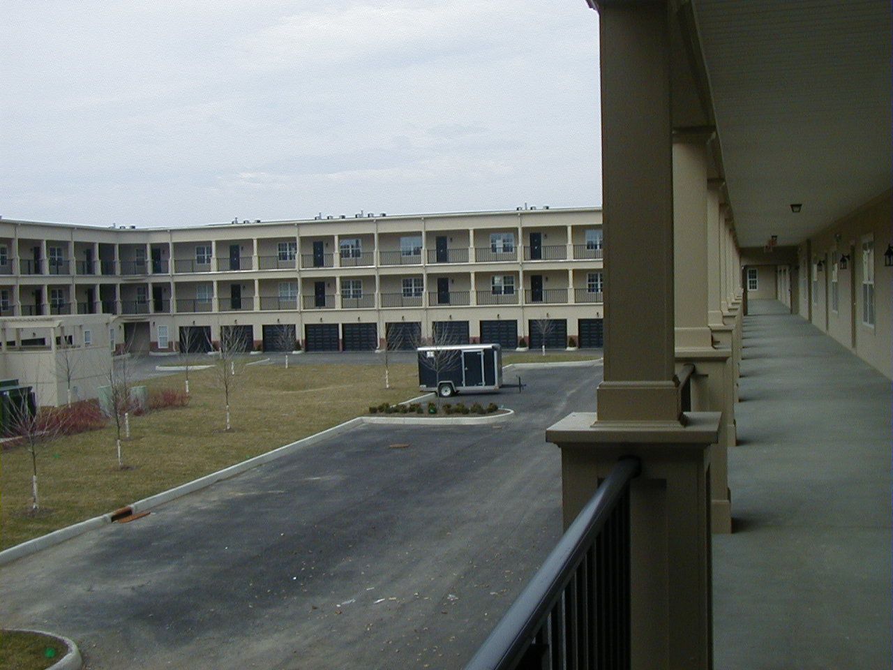 Courtyard of a motel with two-story tan buildings and a long covered walkway on the right