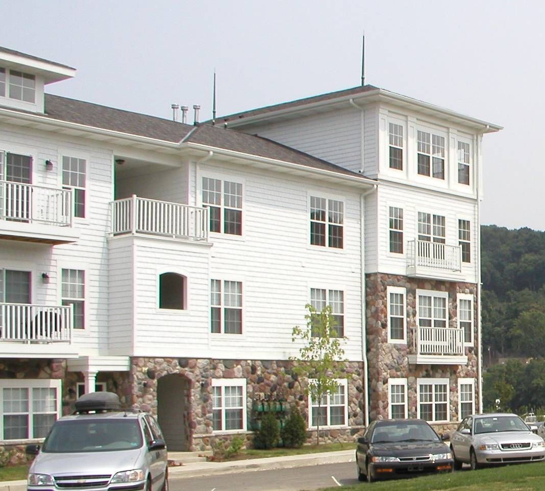 White apartment building with balconies and parked cars in front