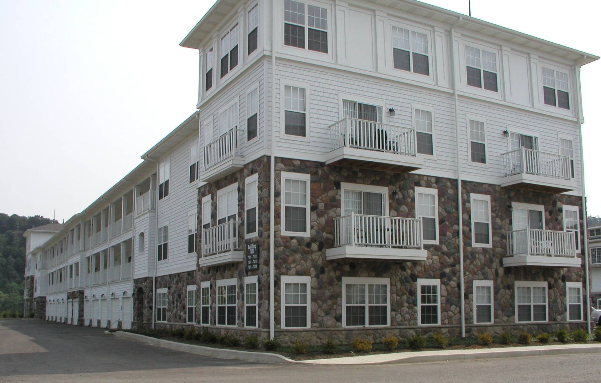 Large white-and-brown apartment building with many windows and balconies on a street corner