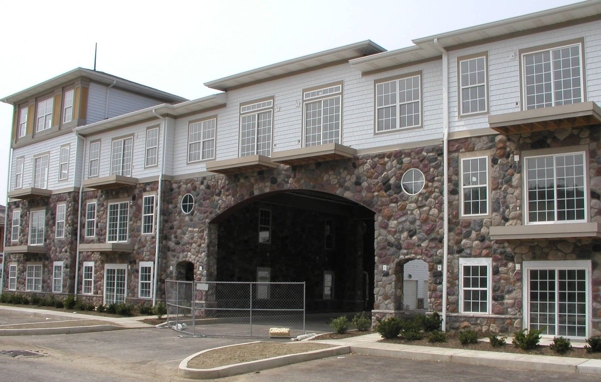 Brick and white building with arched entrance and many windows, viewed from the front